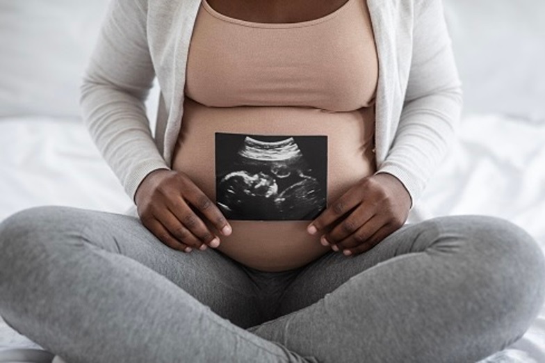 Woman holding stomach and sonogram photo